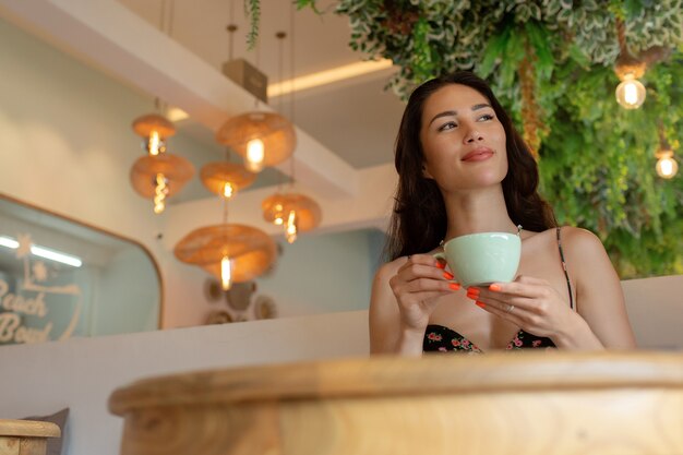 Hermosa chica tomando café en un café