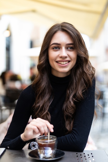 Hermosa chica tomando un café en la cafetería al aire libre