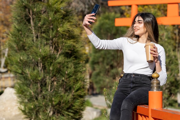 Una hermosa chica tomando selfie en el parque Foto de alta calidad
