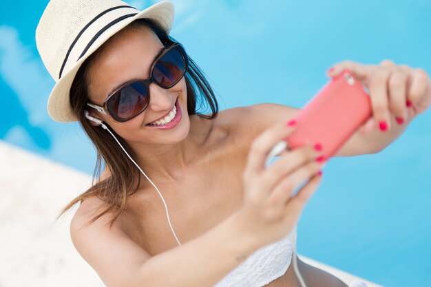 Hermosa chica tomando un selfie en la piscina.