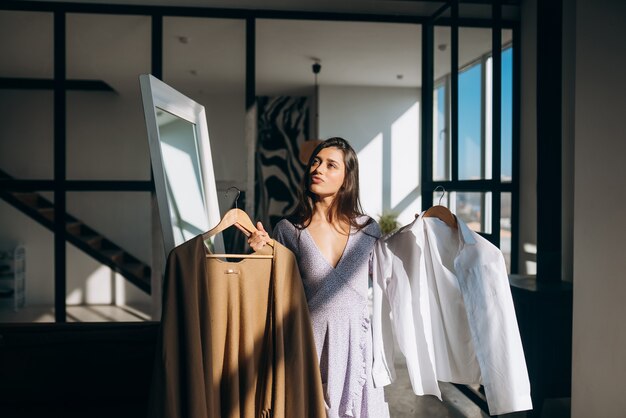 Hermosa chica tratando de vestido en la habitación