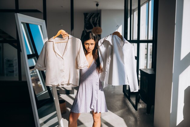 Hermosa chica tratando de vestido en la habitación