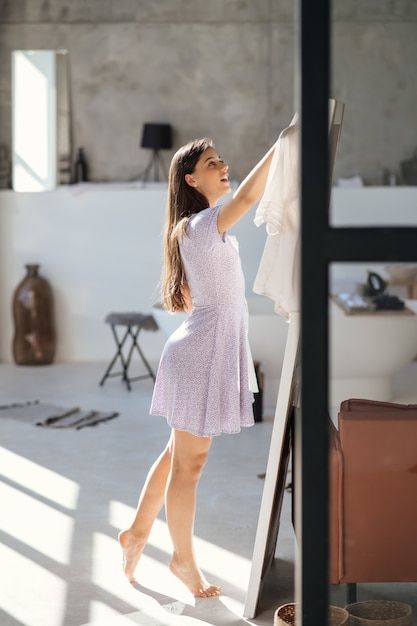 Hermosa chica tratando de vestido en la habitación