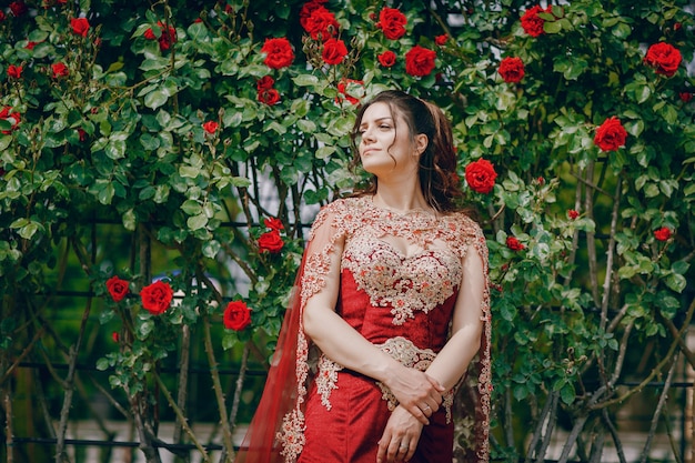 Una hermosa chica turca con un vestido largo rojo camina en la ciudad vieja de verano