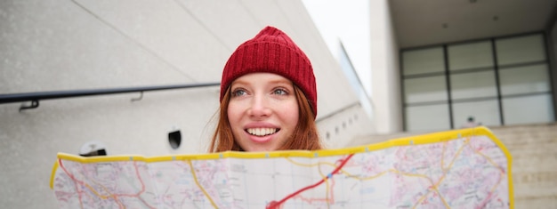 Hermosa chica turista sentada en las escaleras con un mapa de la ciudad planea su viaje busca dirección mientras