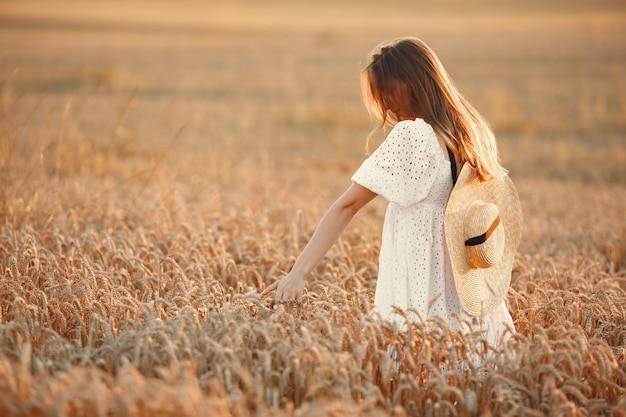 Hermosa chica con un vestido blanco. Mujer en un campo de otoño. Dama con sombrero de paja.