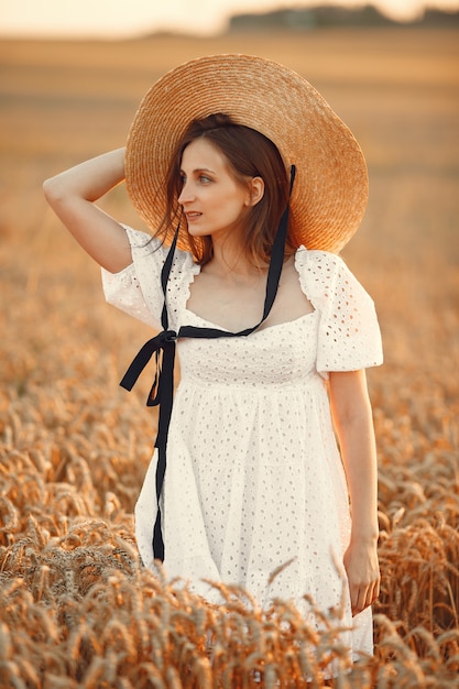 Hermosa chica con un vestido blanco. Mujer en un campo de otoño. Dama con sombrero de paja.