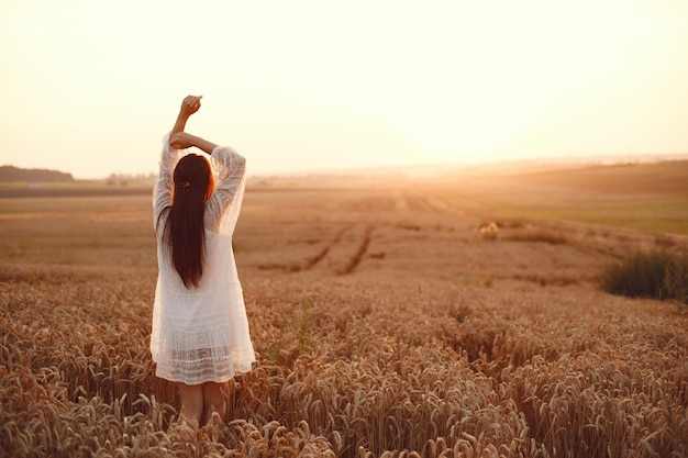 Hermosa chica con un vestido blanco. Mujer en un campo de trigo de otoño.