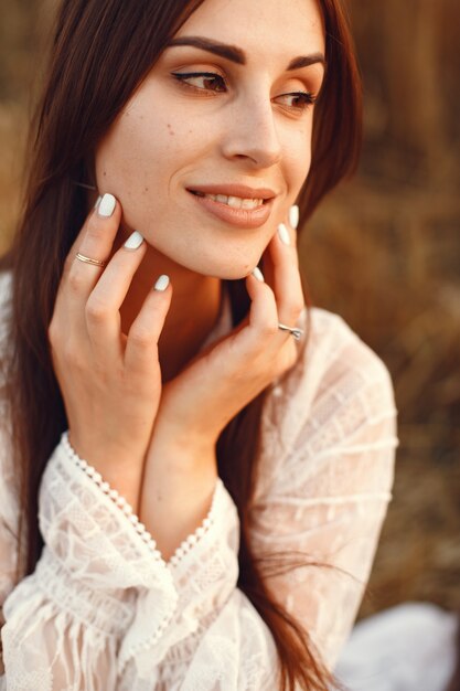 Hermosa chica con un vestido blanco. Mujer en un campo de trigo de otoño.