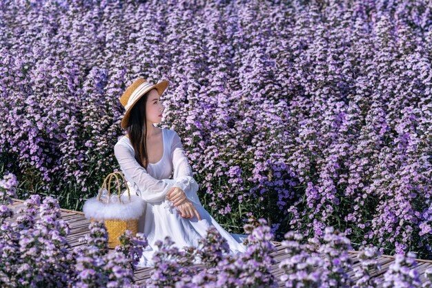 Hermosa chica en vestido blanco sentada en los campos de flores de Margaret