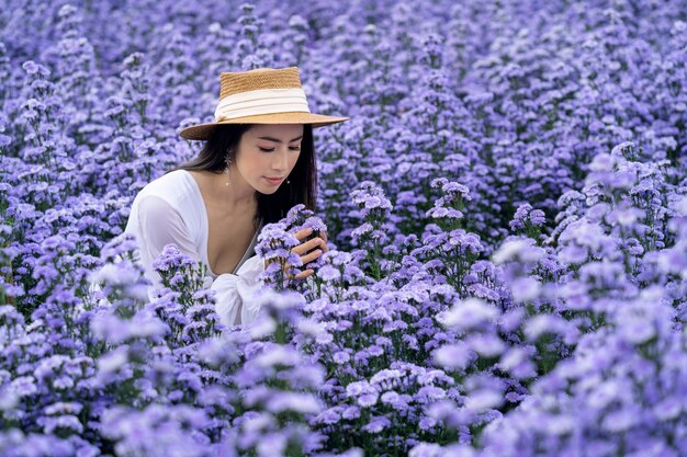 Hermosa chica en vestido blanco sentado en los campos de flores de Margaret, Chiang Mai.