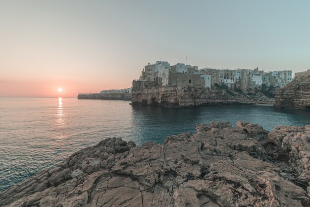 Hermosa ciudad en un acantilado junto al mar con la puesta de sol en el fondo