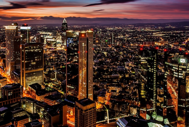 Hermosa ciudad con altos rascacielos brillando bajo el cielo colorido por la noche