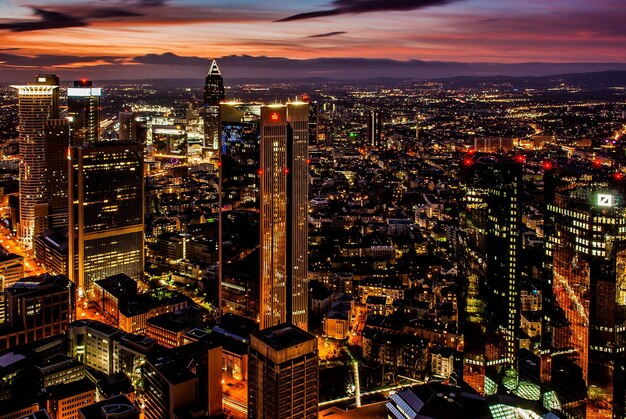 Hermosa ciudad con altos rascacielos brillando bajo el cielo colorido por la noche