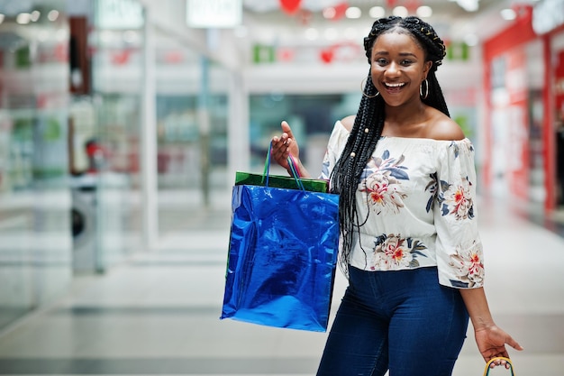 Hermosa cliente afroamericana bien vestida con bolsas de compras de colores en el centro comercial