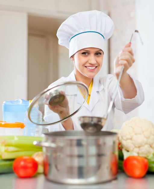 Hermosa cocinera en toque prepara almuerzo vegetariano