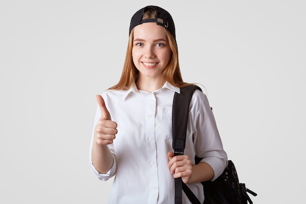 Hermosa colegiala satisfecha mantiene el pulgar levantado