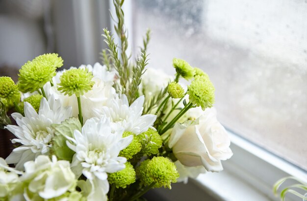 Hermosa composición de flores con flores blancas y verdes cerca de la ventana