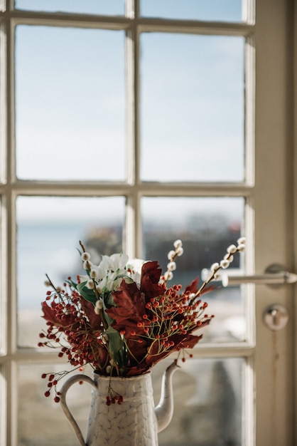 Hermosa composición de flores en una maceta junto a la ventana