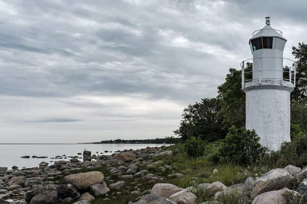 hermosa costa rocosa del mar con una torre de faro blanco al lado