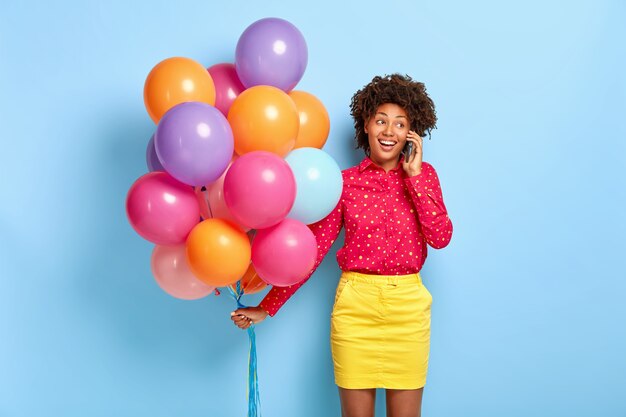 La hermosa cumpleañera afroamericana satisfecha tiene una conversación agradable, recibe felicitaciones de familiares y amigos