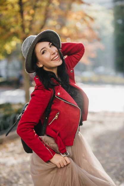 Hermosa dama sonriente con cabello negro disfrutando del día de otoño