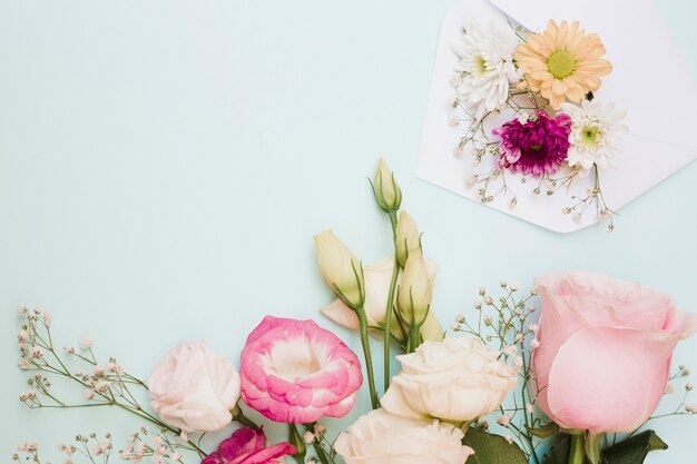 Hermosa decoración de flores frescas con sobre en el fondo de color