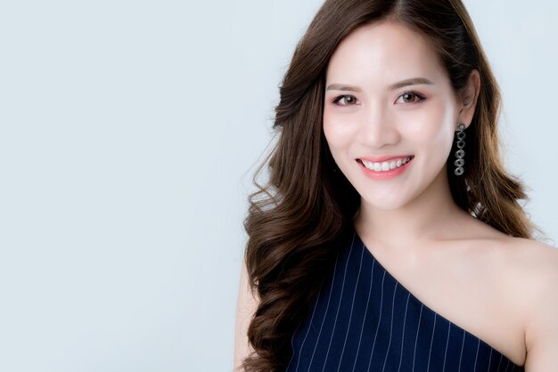 Hermosa elegancia atractiva mujer asiática en vestido azul mano toque cara modelo pose en estudio sesión de fotos aislar fondo blanco