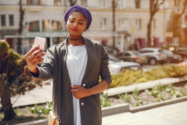 Una hermosa y elegante chica de piel oscura camina en una soleada ciudad veraniega