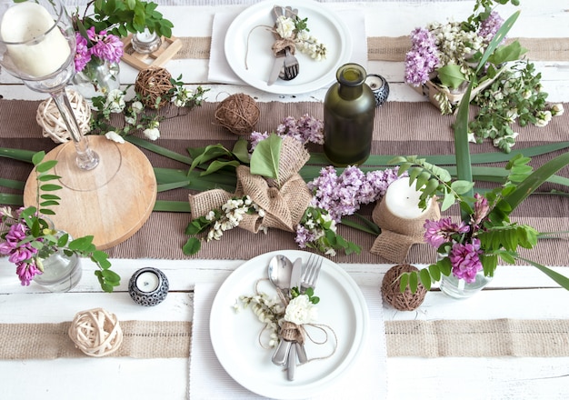 Hermosa y elegante mesa decorada para vacaciones: boda o día de San Valentín con cubiertos modernos, arco, vidrio, velas y regalos.