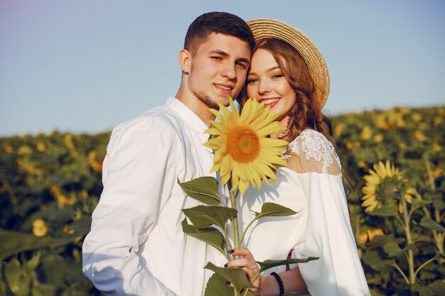 Hermosa y elegante pareja en un campo con girasoles