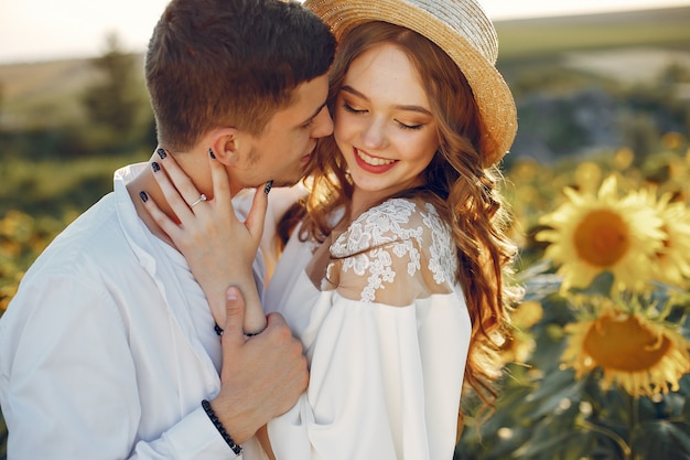 Hermosa y elegante pareja en un campo con girasoles