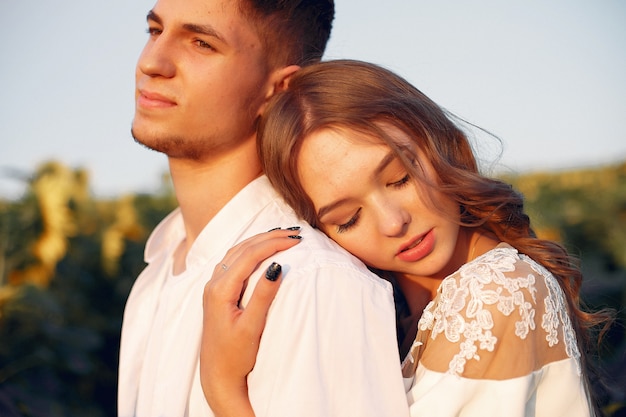 Hermosa y elegante pareja en un campo con girasoles