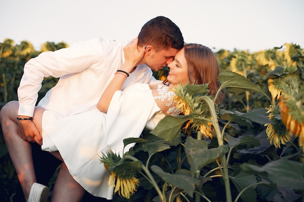 Hermosa y elegante pareja en un campo con girasoles