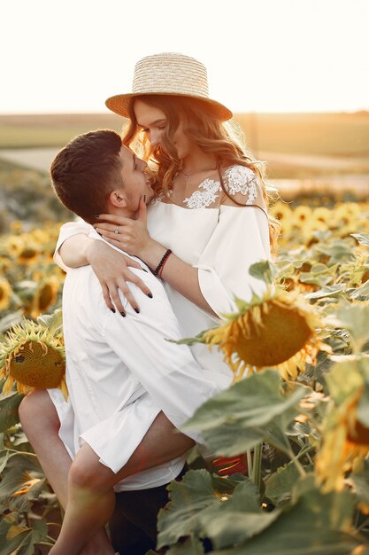 Hermosa y elegante pareja en un campo con girasoles