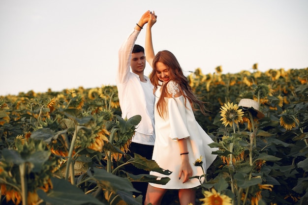 Hermosa y elegante pareja en un campo con girasoles