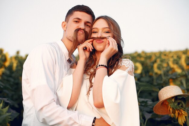 Hermosa y elegante pareja en un campo con girasoles