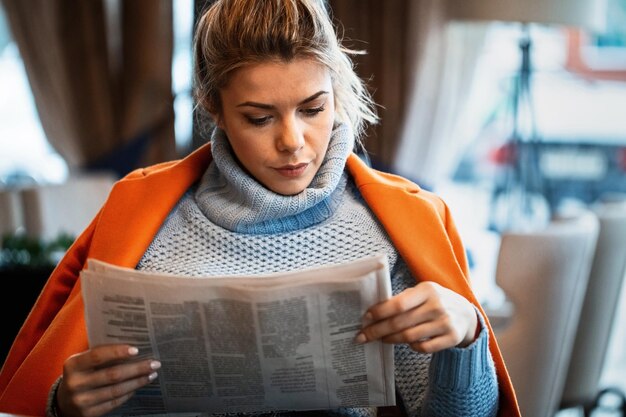 Hermosa empresaria leyendo el periódico mientras se relaja en un café