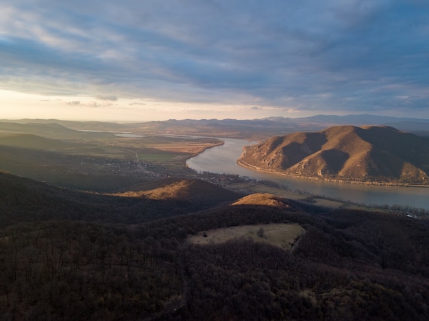 Hermosa escena de un río entre colinas y bosques bajo el cielo nublado