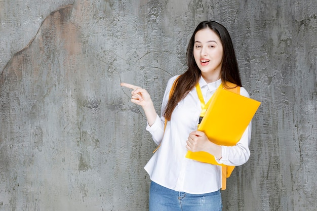 Hermosa estudiante con camisa blanca sosteniendo un libro. foto de alta calidad