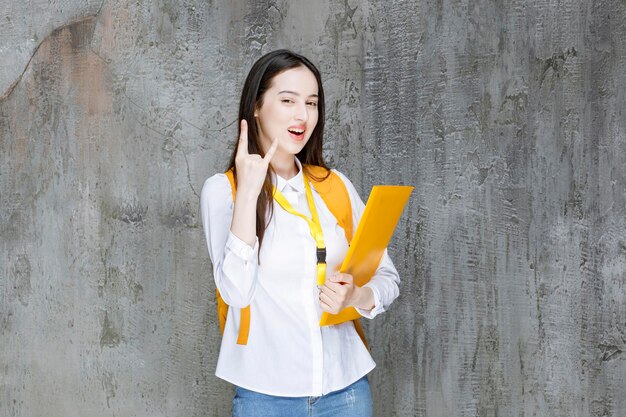 Hermosa estudiante con camisa blanca sosteniendo un libro. foto de alta calidad