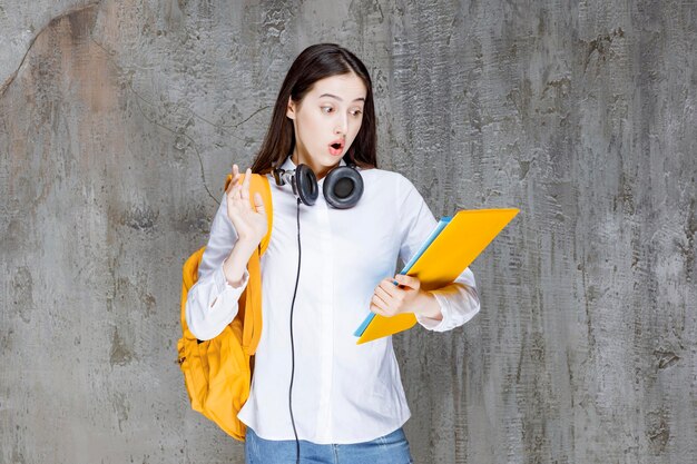 Hermosa estudiante con mochila mirando notas en libros. foto de alta calidad