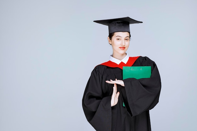 Hermosa estudiante de posgrado con diploma de pie. Foto de alta calidad