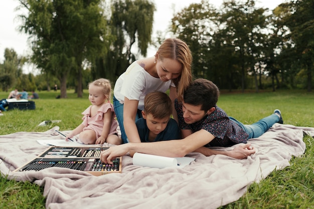 Foto gratuita hermosa familia pasa tiempo juntos, dibujando en la naturaleza