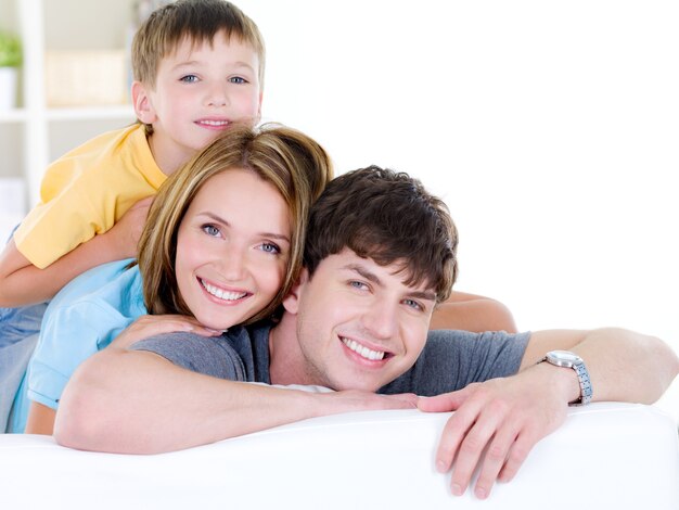 Hermosa familia sonriente feliz de tres personas con hijo - en el interior