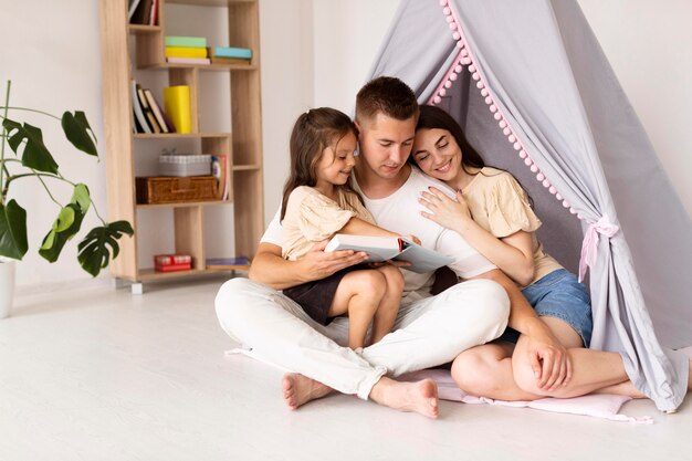 Hermosa familia de tiro largo pasar tiempo juntos en casa con espacio de copia