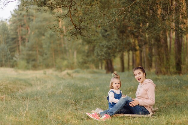 Hermosa y feliz madre e hija pasando un buen rato en el bosque