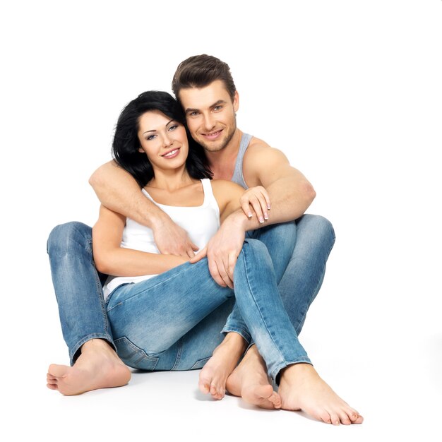 Hermosa feliz pareja de enamorados en el espacio en blanco vestida con jeanse azul y camiseta blanca