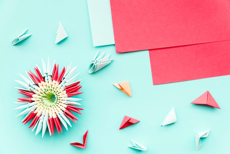 Foto gratuito hermosa flor de origami hecha con papel rojo sobre fondo verde azulado