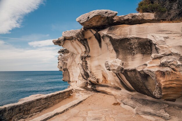 Hermosa foto de un acantilado rocoso cerca del mar con un cielo azul